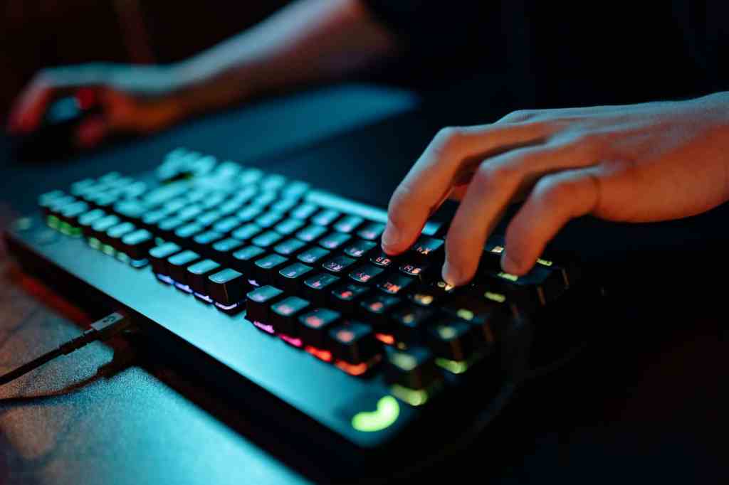 Closeup on the hand of a person using a gaming keyboard.